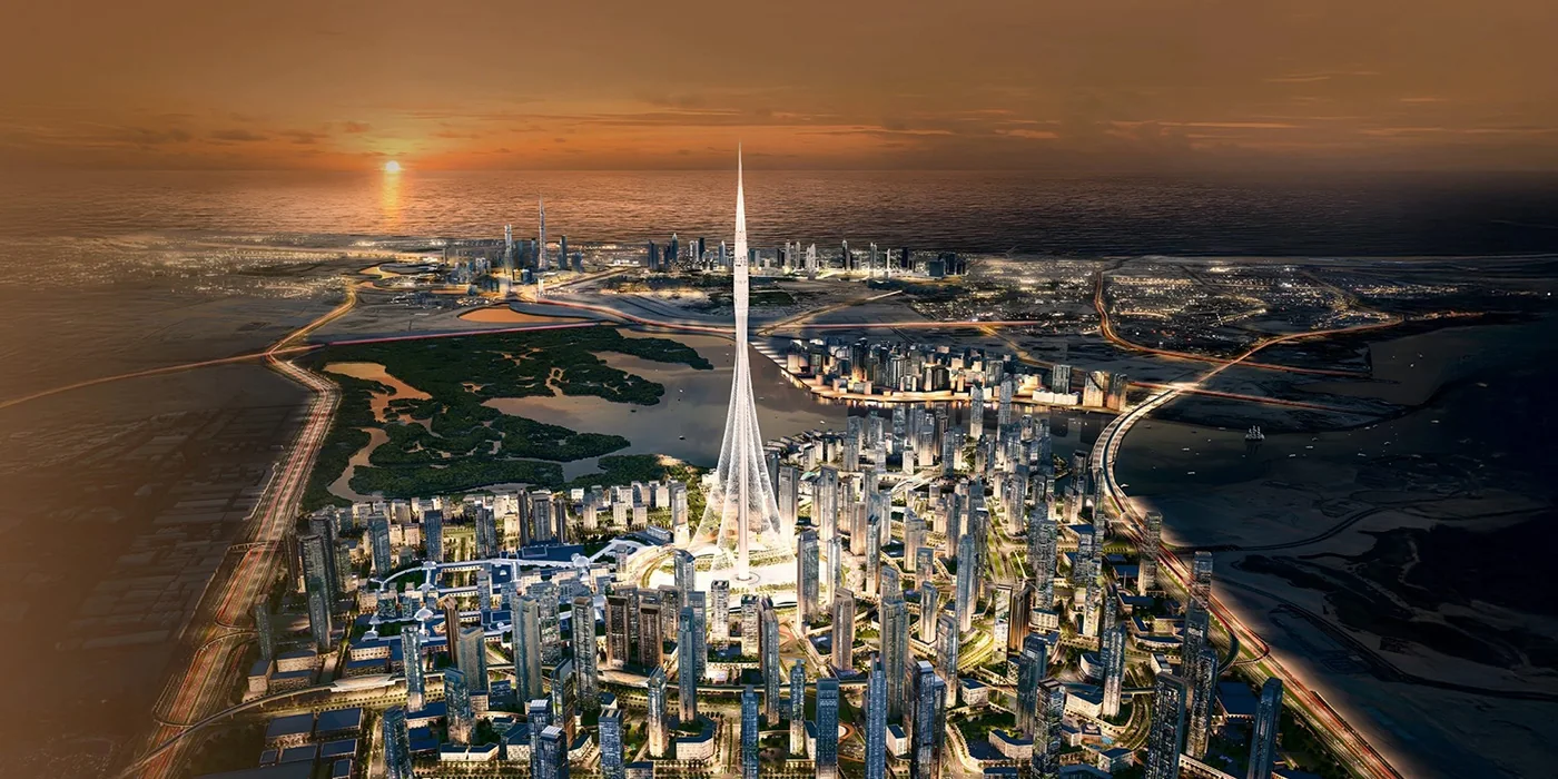 Aerial view of the Dubai Creek Harbour masterplan at sunset, with Dubai Creek Tower at its centre and the Ras Al Khor wetlands beyond